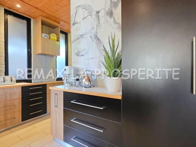 Modern kitchen featuring two-tone cabinetry, timber ceiling paneling, and light-colored floor tiles, creating a contemporary and warm aesthetic.