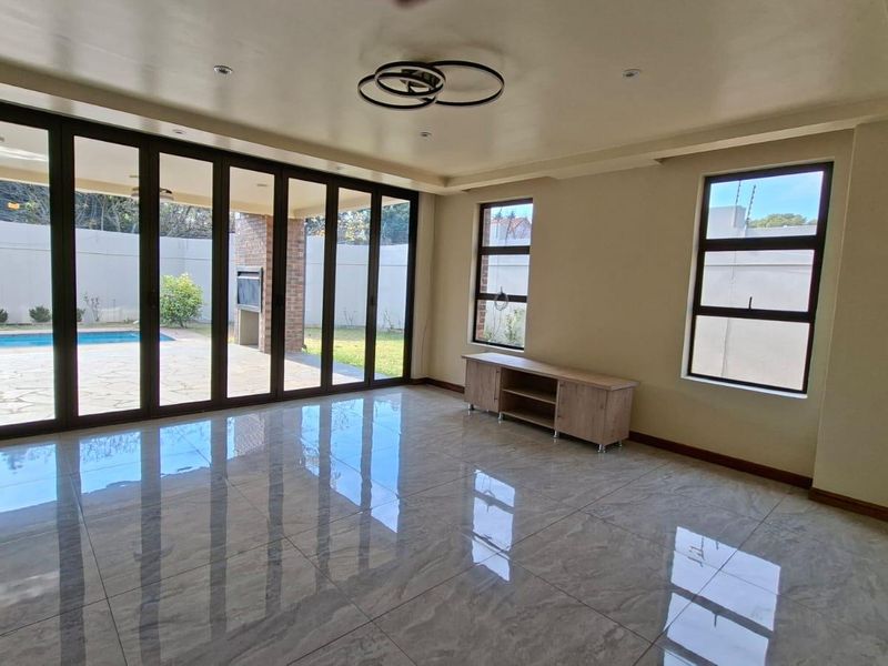 Spacious living area featuring large format floor tiles, modern recessed ceiling lighting, and expansive aluminium stacker doors providing seamless access to the outdoor patio.