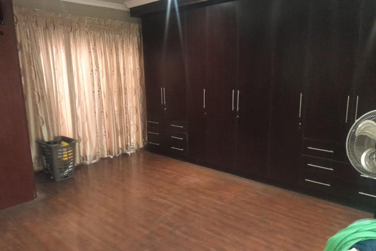 A bedroom featuring extensive dark wood built-in cabinetry and laminate flooring, providing ample storage space.