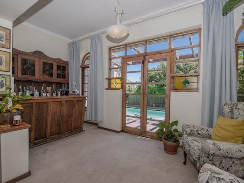 A well-maintained bar area featuring a built-in wooden bar, decorative stained glass accents, and timber-framed doors opening to a pool area.