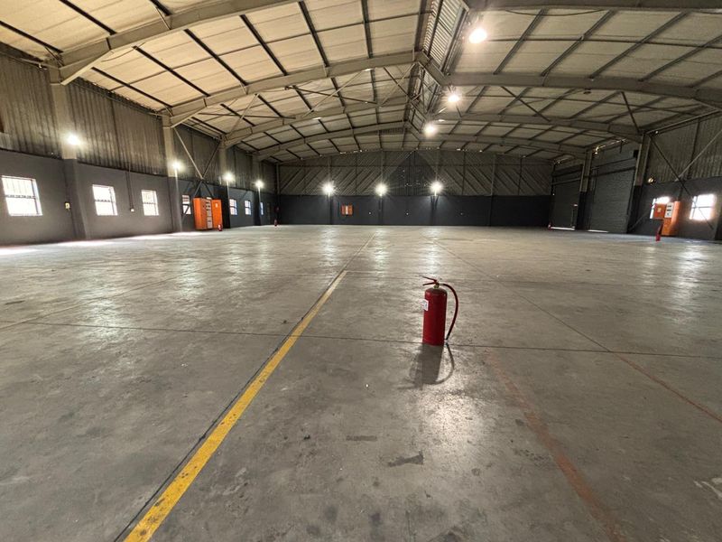 Spacious industrial warehouse featuring high ceilings, concrete flooring, and integrated high bay lighting, suitable for storage or manufacturing operations.