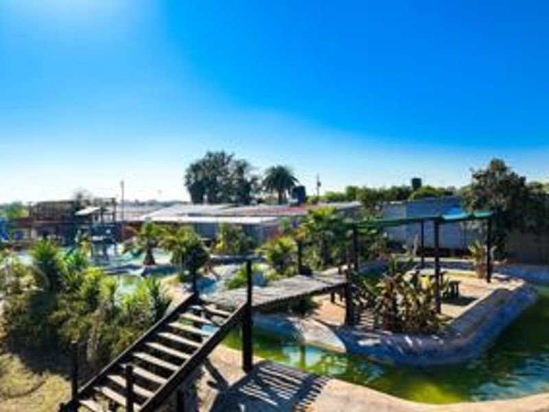 Outdoor pool area featuring a wooden bridge, pergola, and landscaped garden elements on a small holding property.