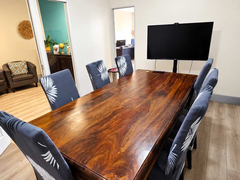 A well-maintained office meeting room featuring wood-look laminate flooring and neutral walls, providing a professional space for collaboration.