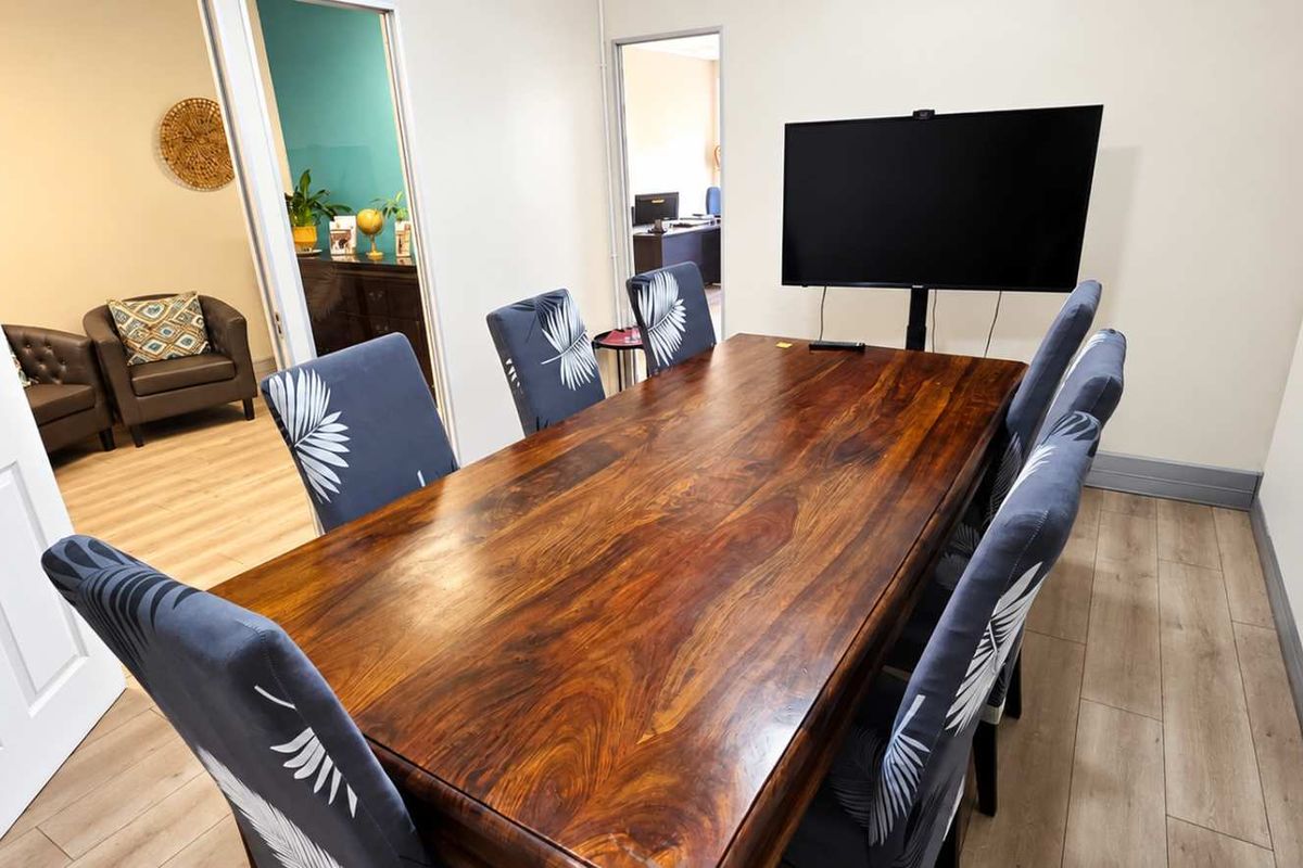 A well-maintained office meeting room featuring wood-look laminate flooring and neutral walls, providing a professional space for collaboration.