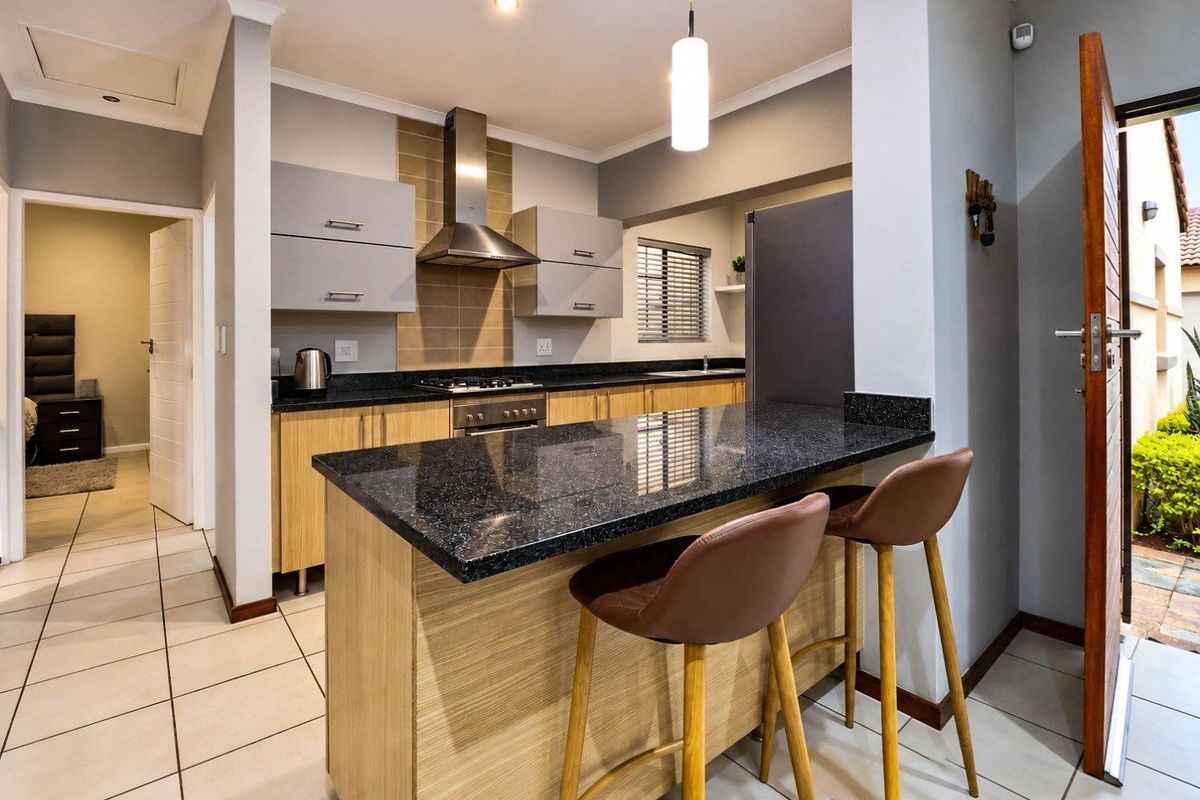 Modern kitchen featuring granite countertops, light wood cabinetry, a breakfast nook, and stainless steel appliances, with direct access to an outdoor area.