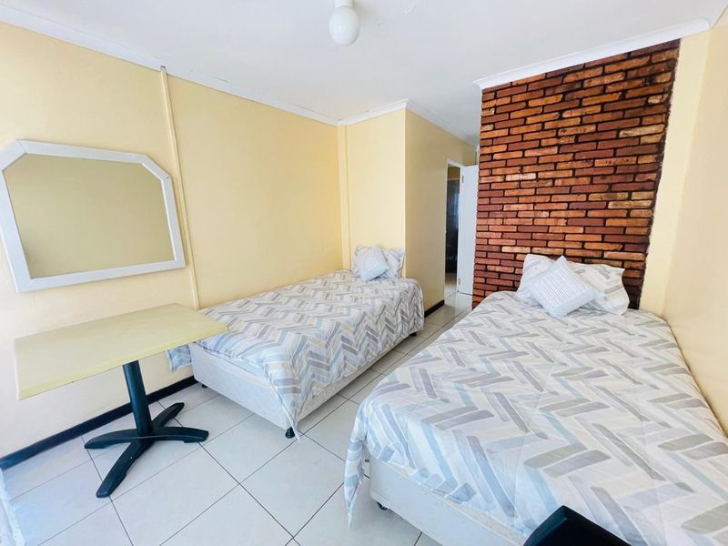 A bedroom featuring an exposed brick accent wall, tiled flooring, and coved ceiling details.