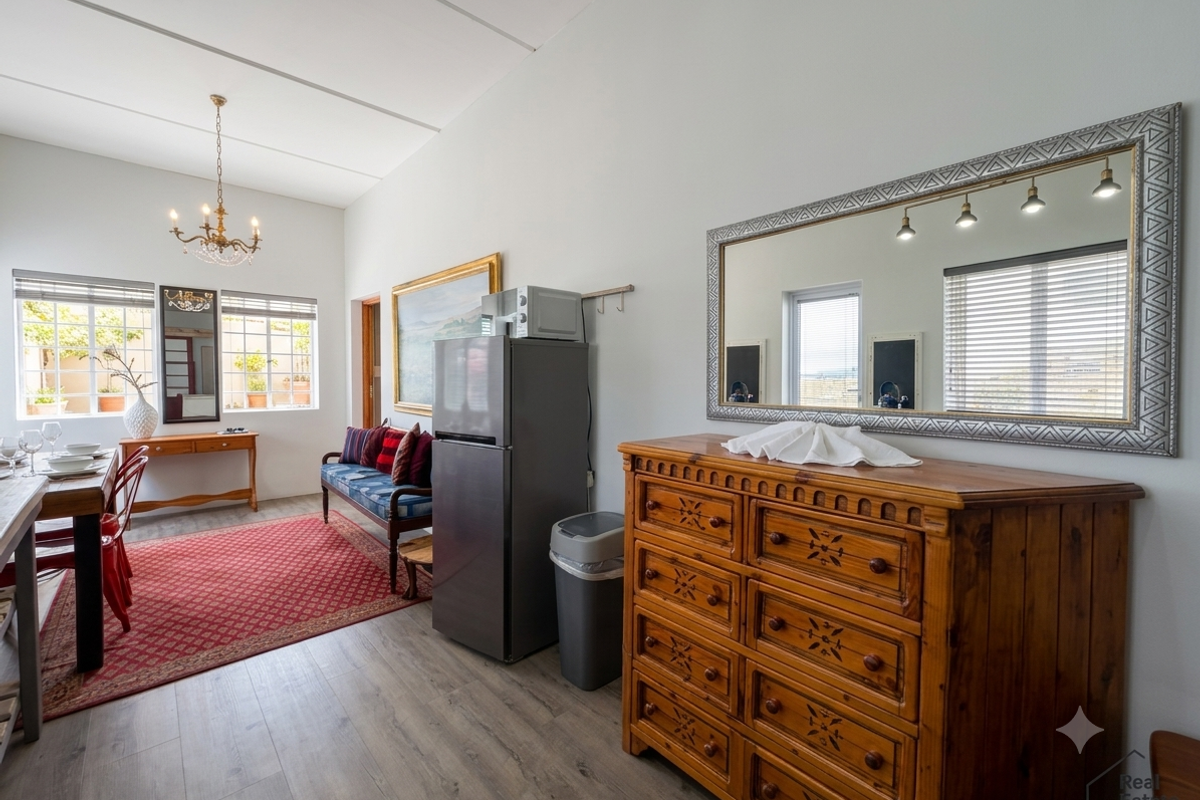 A bright living area featuring laminate flooring, neutral walls, and large windows with venetian blinds, offering a clean and well-maintained space.