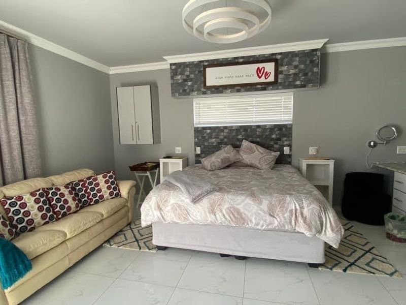 A spacious bedroom featuring tiled flooring, built-in cabinetry, and a dedicated vanity area with a stone countertop.