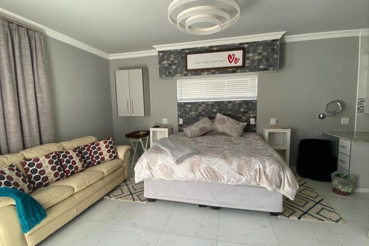 A spacious bedroom featuring tiled flooring, built-in cabinetry, and a dedicated vanity area with a stone countertop.