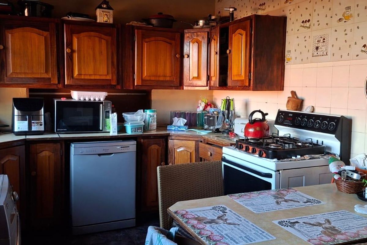 A traditional kitchen featuring dark wood cabinetry, tiled walls, and a freestanding gas stove, offering a functional layout with ample storage space.
