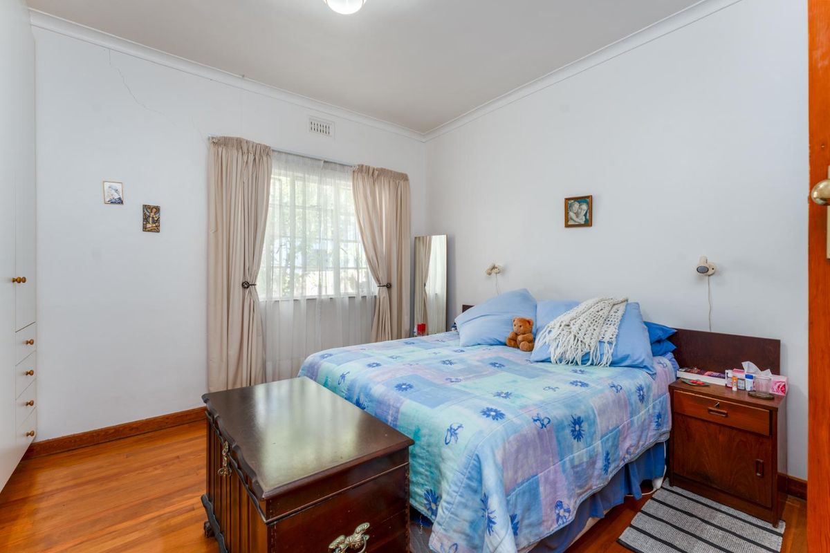 A bedroom featuring polished timber flooring, built-in wardrobe storage, and a window with natural light.