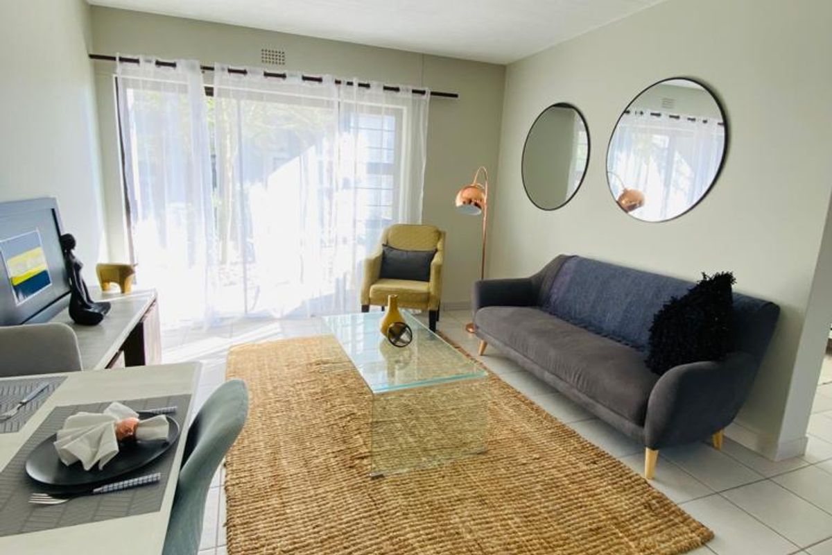 A bright and well-maintained living room featuring tiled flooring, a tongue and groove ceiling, and a sliding glass door providing natural light.