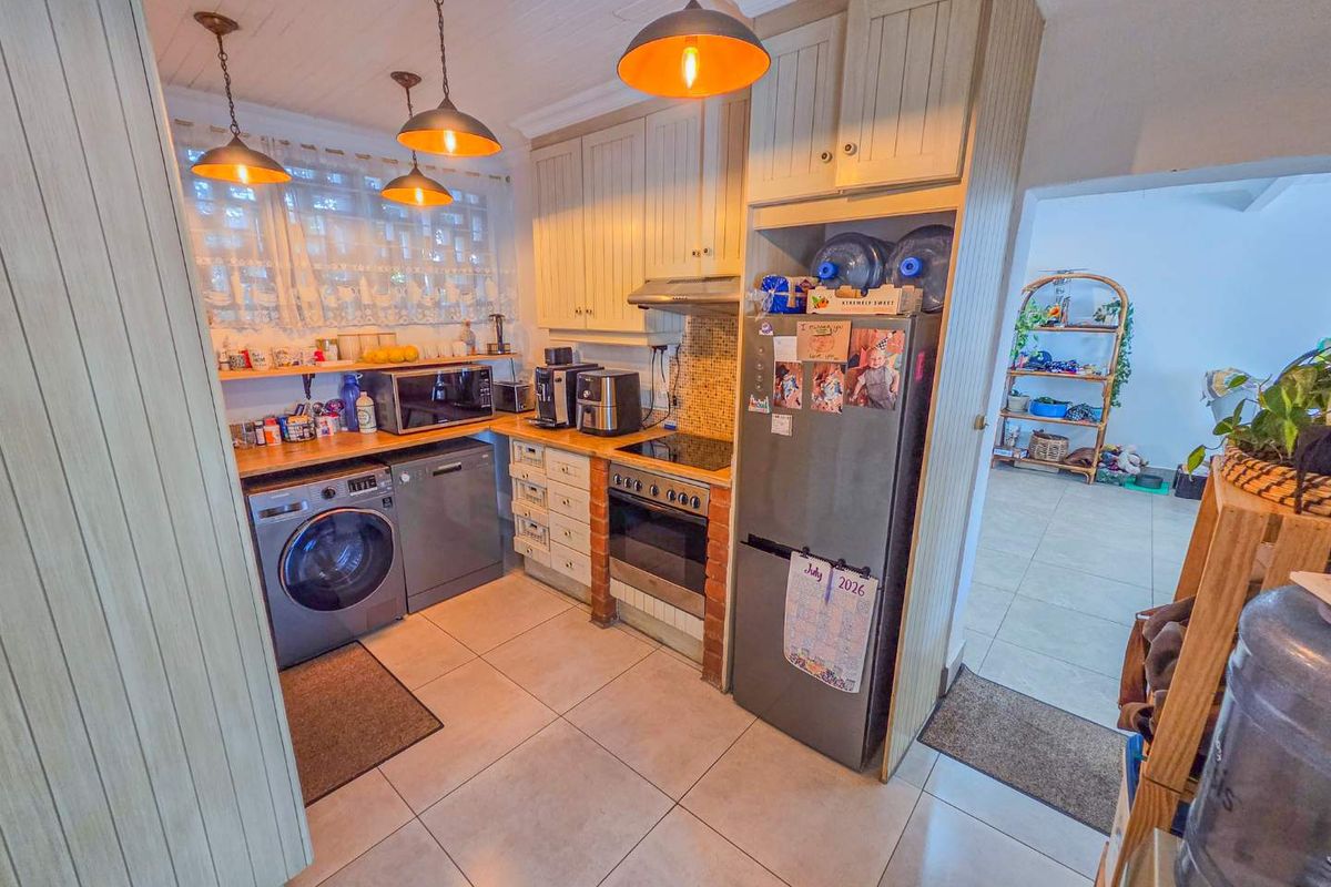 A functional kitchen featuring built-in cabinetry, tiled flooring, a built-in oven with hob, and pendant lighting, offering a practical layout for daily use.