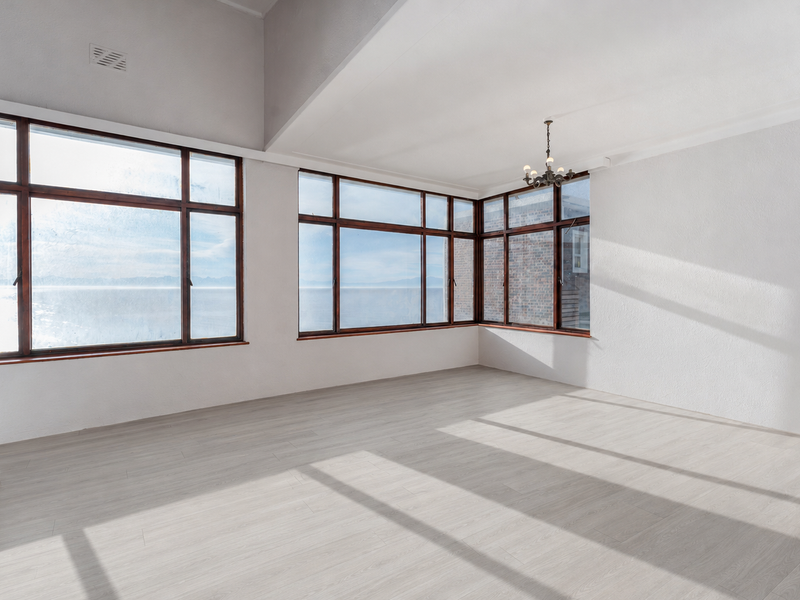Spacious living area featuring vaulted ceilings, light laminate flooring, a brick fireplace, and expansive windows offering natural light and scenic views.