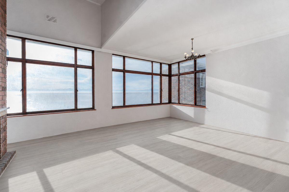 Spacious living area featuring vaulted ceilings, light laminate flooring, a brick fireplace, and expansive windows offering natural light and scenic views.
