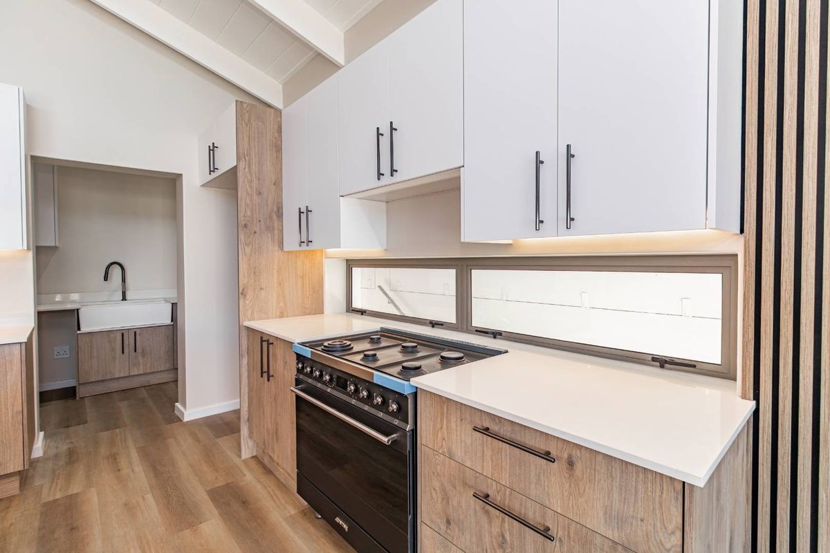 Modern kitchen featuring white and wood-grain cabinetry, quartz countertops, a gas hob, and an integrated scullery area with a farmhouse sink.