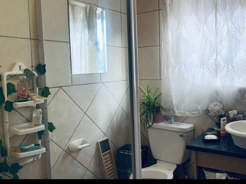 A functional bathroom featuring tiled walls, a vanity with a basin, and a standard toilet setup.