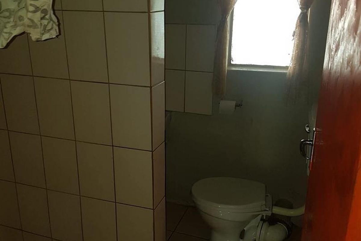 A functional bathroom featuring a toilet and a tiled shower area, requiring cosmetic updates to modernize the space.