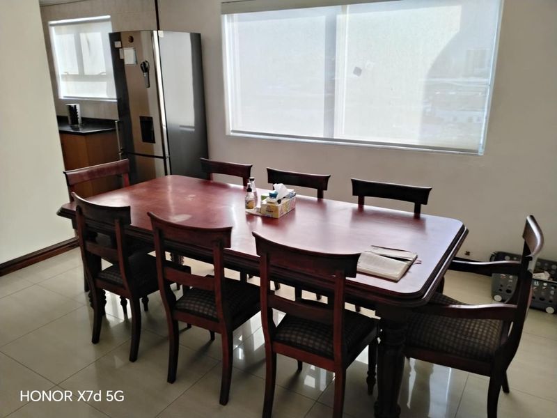 A dining area featuring tiled flooring and large windows with roller blinds, providing a functional space for meals.