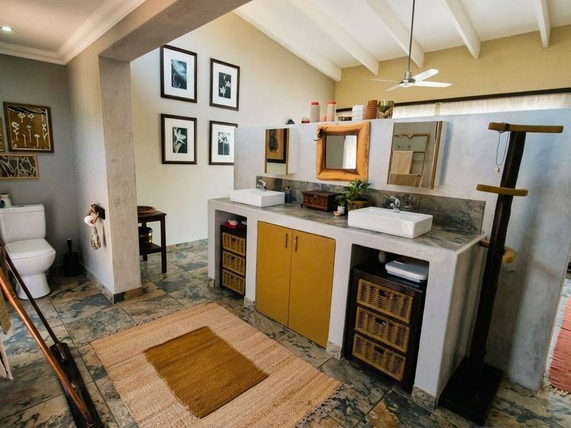 Spacious bathroom featuring a double vanity with vessel sinks, vaulted ceilings with exposed beams, and tiled flooring in a neutral, contemporary style.