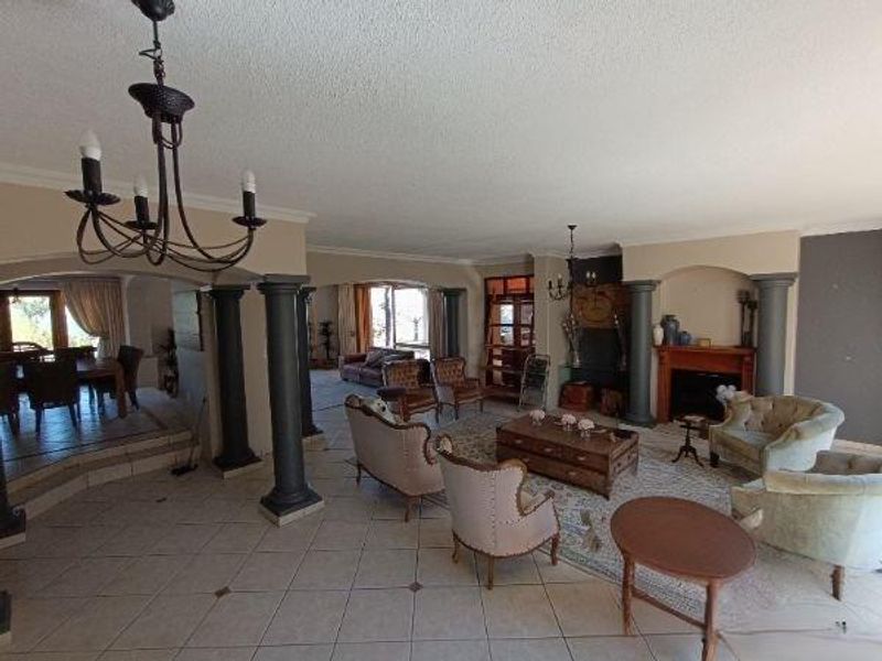 Spacious open-plan living area featuring tiled floors, decorative columns, and a fireplace, creating a versatile space for relaxation and dining.