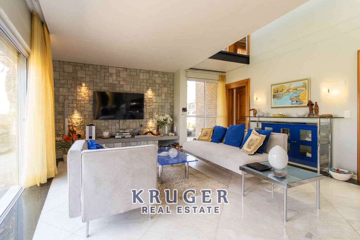 Spacious living room featuring a textured stone feature wall, large windows, and polished tile flooring with an open-plan layout.