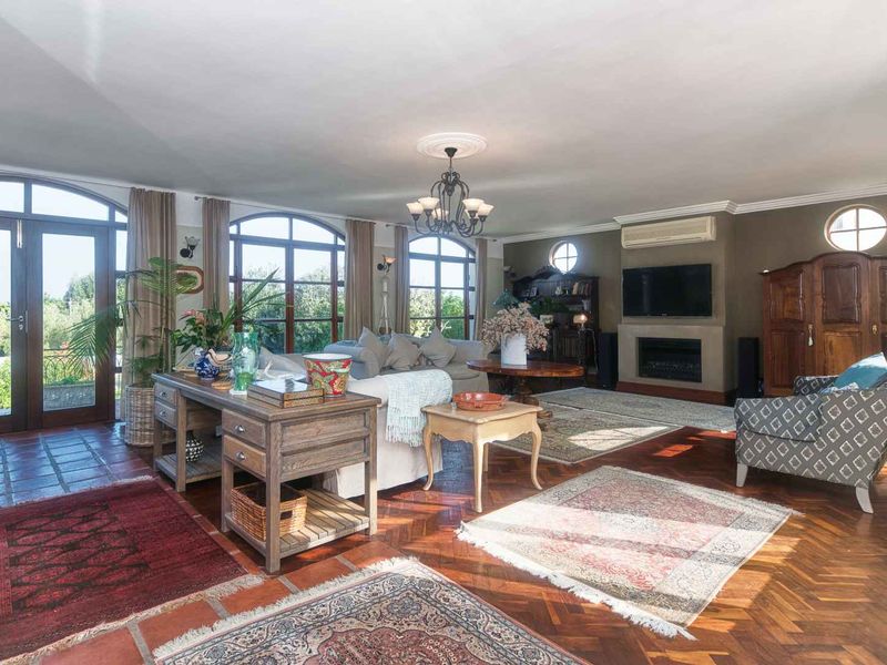 Spacious living room featuring classic parquet flooring, arched windows with garden access, a built-in fireplace, and a wall-mounted air conditioning unit.