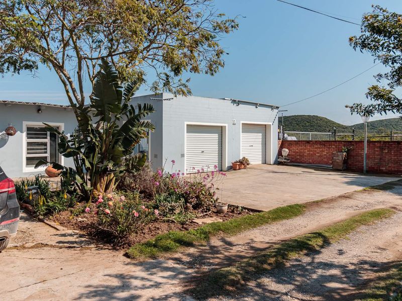 Front exterior view of the property featuring a double garage with roll-up doors, a concrete driveway, and a landscaped garden area.