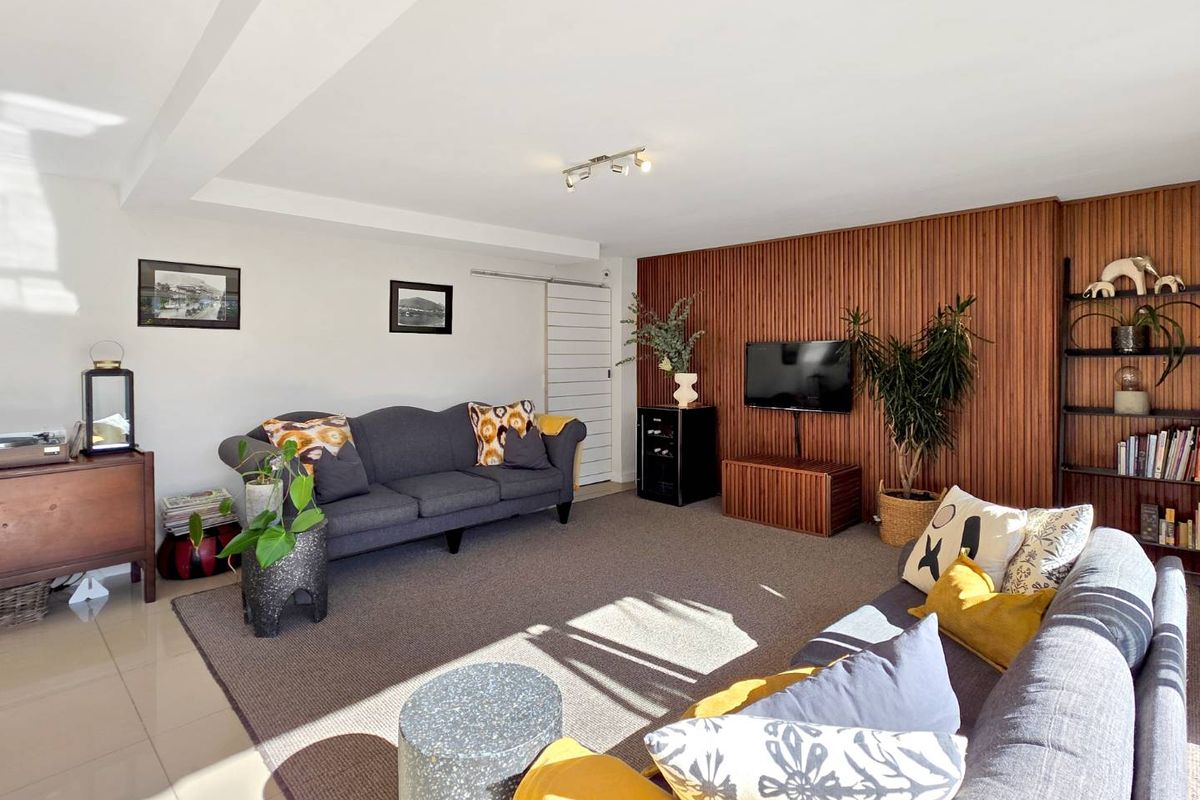 A bright and spacious living room featuring a modern timber slat feature wall, tiled flooring, and contemporary track lighting.