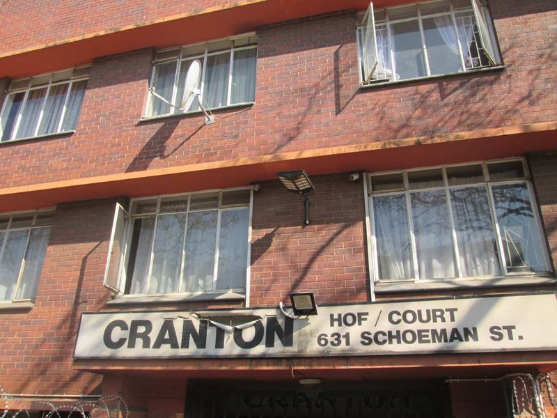 Exterior view of the Cranton Hof/Court apartment building facade, featuring red brick construction and steel-framed windows.