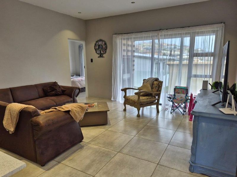 A living room featuring large sliding glass doors that provide natural light and access to the exterior, complemented by neutral tiled flooring.