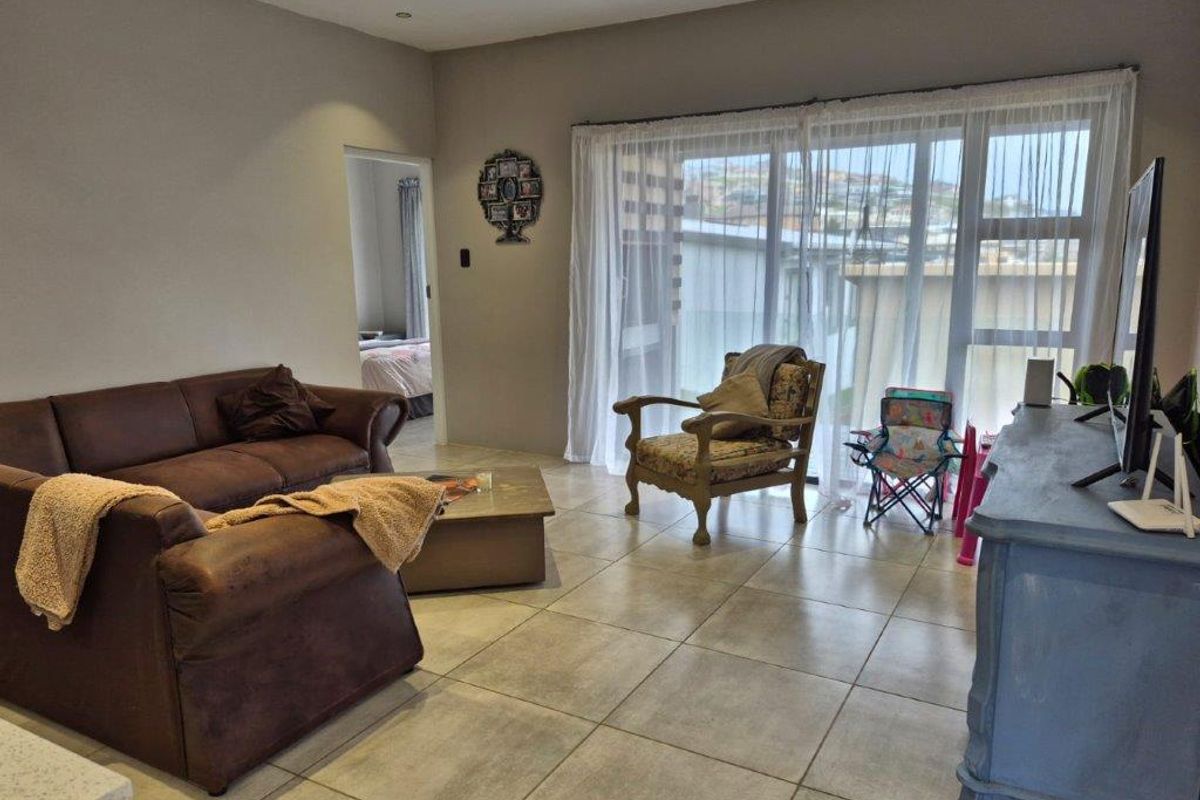 A living room featuring large sliding glass doors that provide natural light and access to the exterior, complemented by neutral tiled flooring.