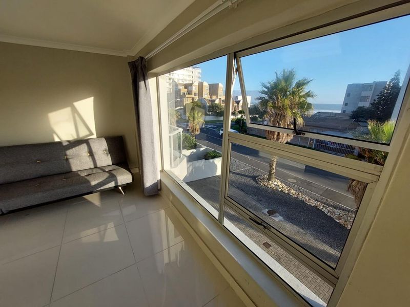 A bright living area featuring large aluminium-framed windows that provide ample natural light and views of the surrounding neighbourhood.