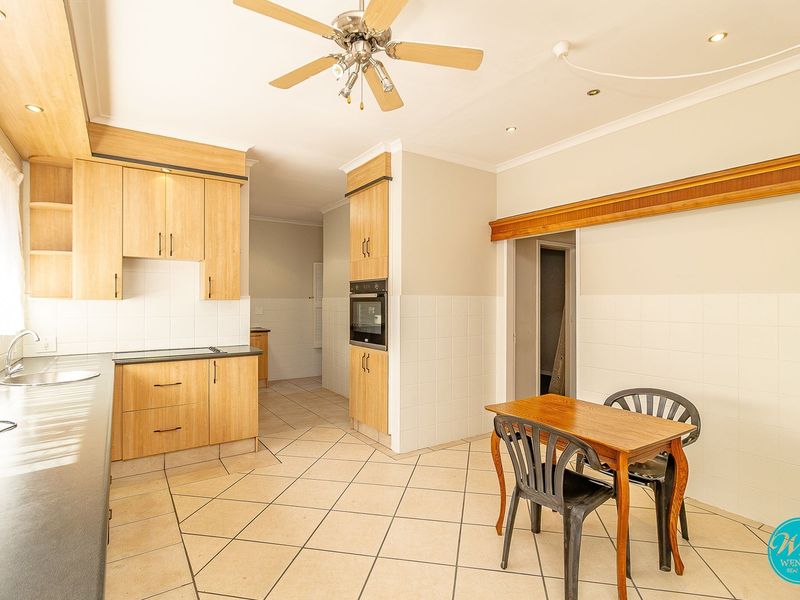 Functional kitchen featuring light wood cabinetry, tiled backsplash, built-in oven, and ceramic tile flooring with an adjacent dining area.