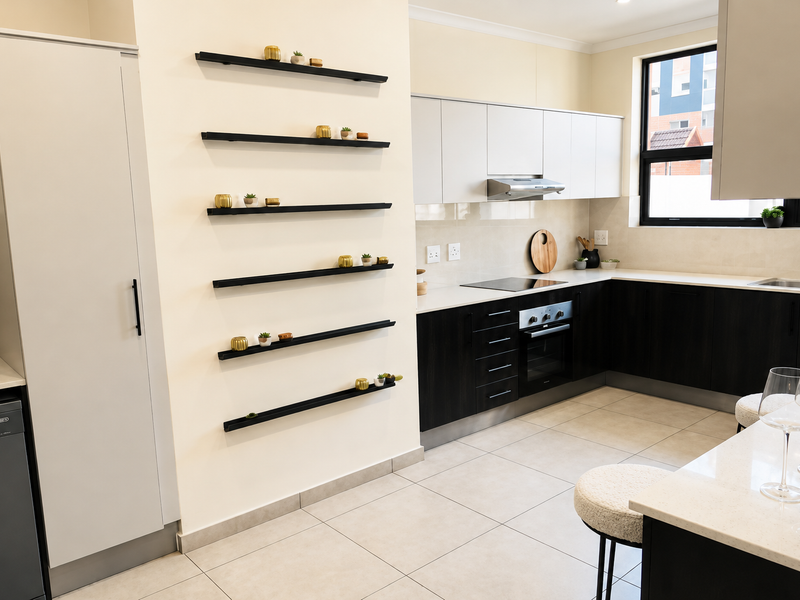 Modern kitchen featuring dark lower cabinetry, light upper cabinets, stone countertops, integrated appliances, and sleek floating wall shelving.