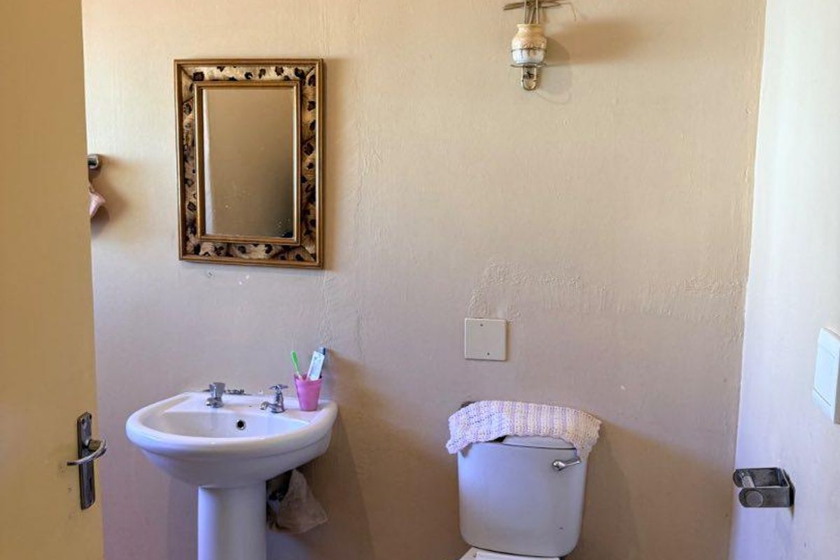 A compact bathroom featuring a pedestal basin and a standard toilet, requiring cosmetic updates to improve the overall finish and aesthetic appeal.