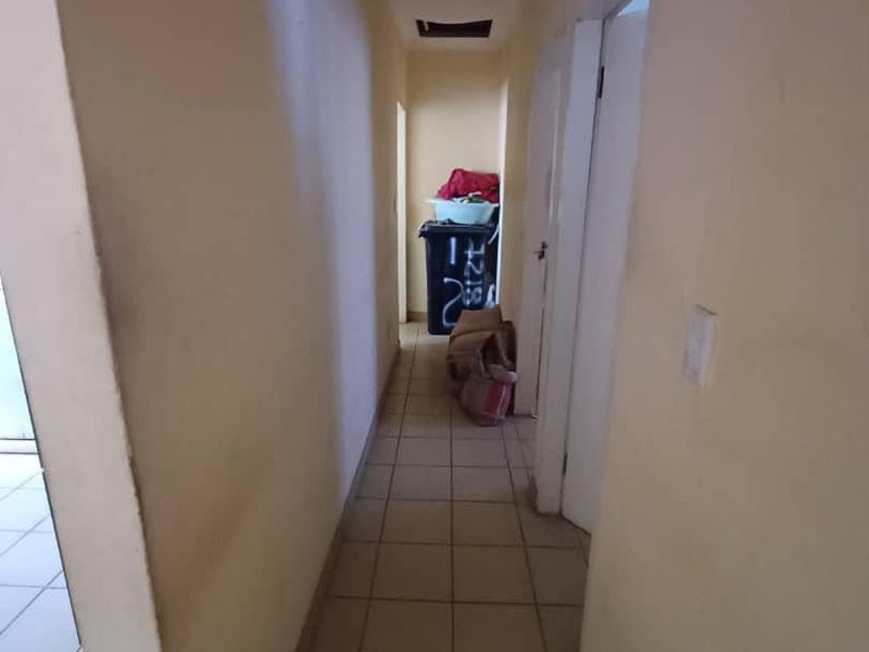 A narrow residential hallway featuring tiled flooring and plain walls, requiring minor cosmetic updates to improve the overall aesthetic.