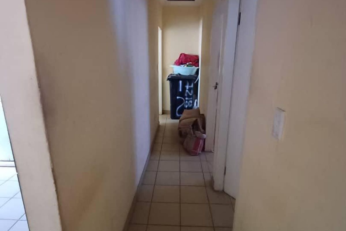 A narrow residential hallway featuring tiled flooring and plain walls, requiring minor cosmetic updates to improve the overall aesthetic.