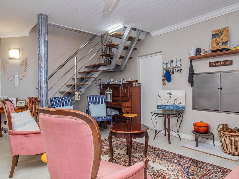 Open plan living area featuring a modern metal staircase, built-in fireplace, and light-toned flooring, creating a functional and inviting space.