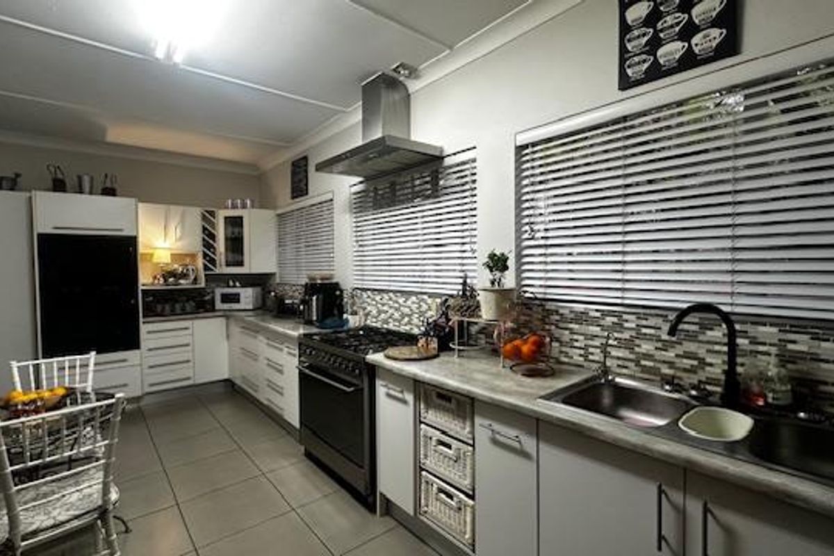 A functional kitchen featuring built-in cabinetry, a stainless steel extractor fan, gas stove, and a double basin sink with a tiled backsplash.