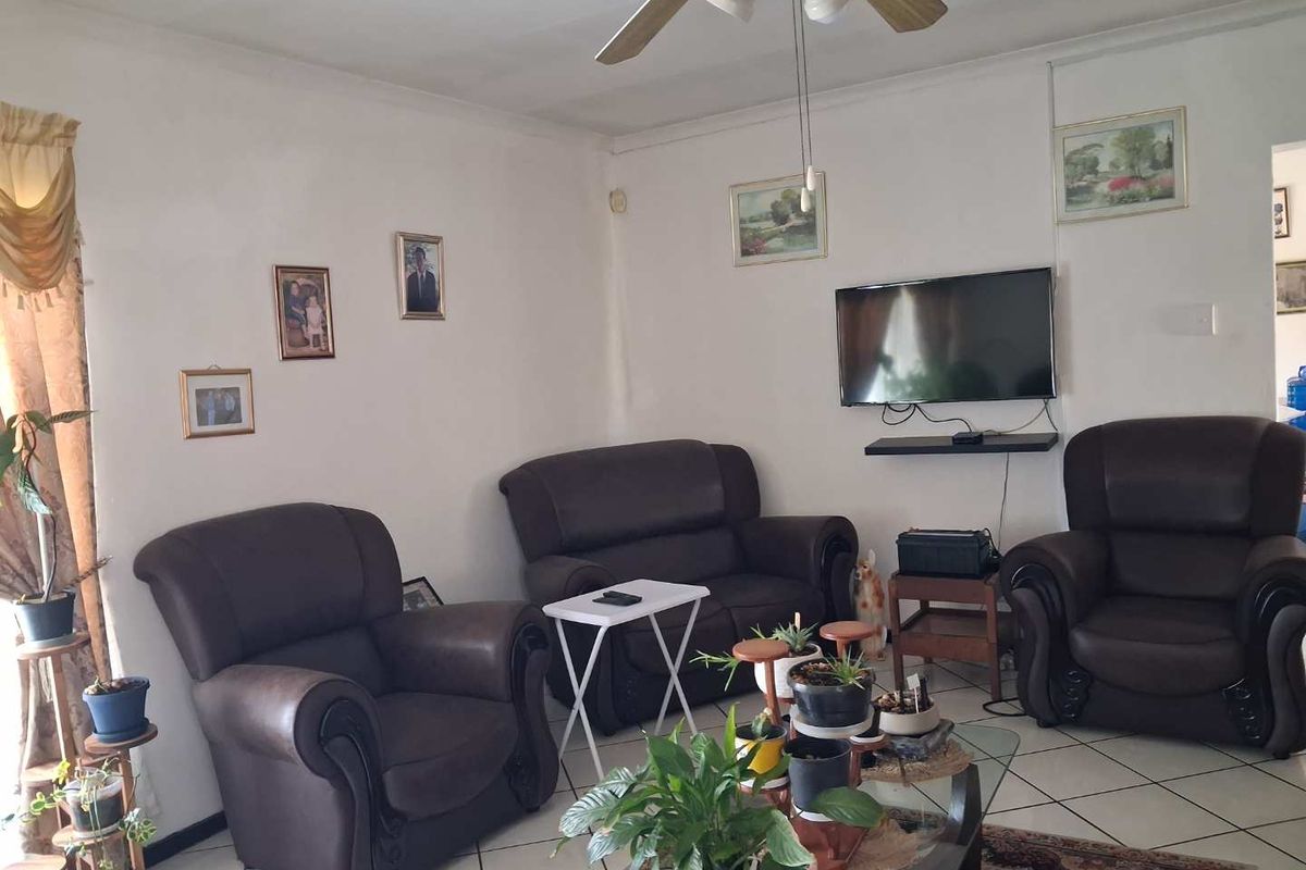A comfortable living room featuring tiled flooring and a ceiling fan, providing a functional and inviting space for relaxation.