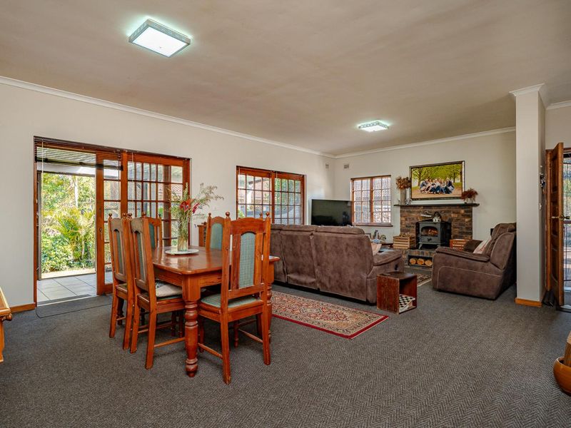 Spacious open-plan living and dining area featuring a brick fireplace with a wood-burning stove and direct access to an outdoor patio through sliding doors.