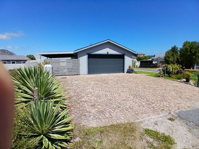 Front view of the property featuring a paved driveway, a single garage, and an attached carport with perimeter fencing.