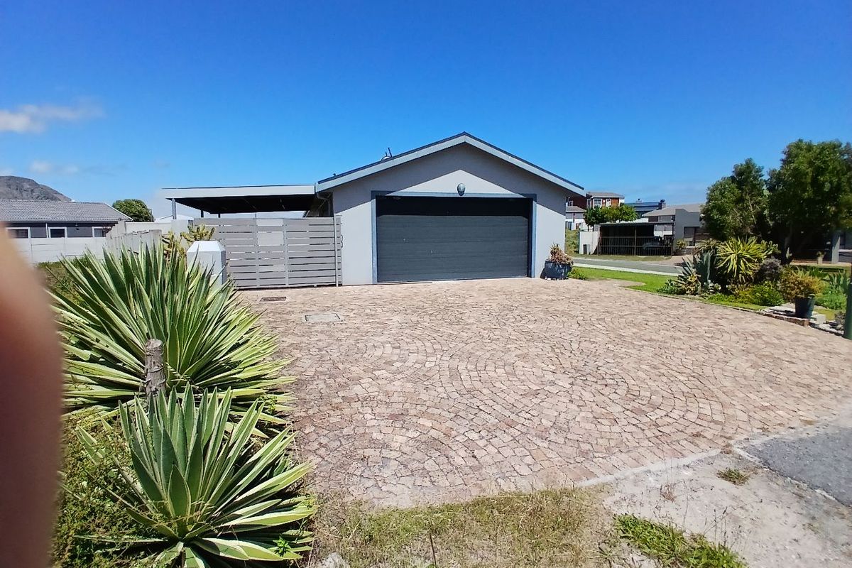 Front view of the property featuring a paved driveway, a single garage, and an attached carport with perimeter fencing.