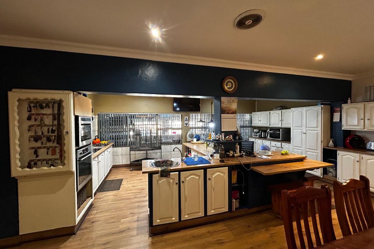 Spacious kitchen featuring a central island, built-in oven, microwave, and ample cabinetry, offering a functional layout with potential for modern updates.