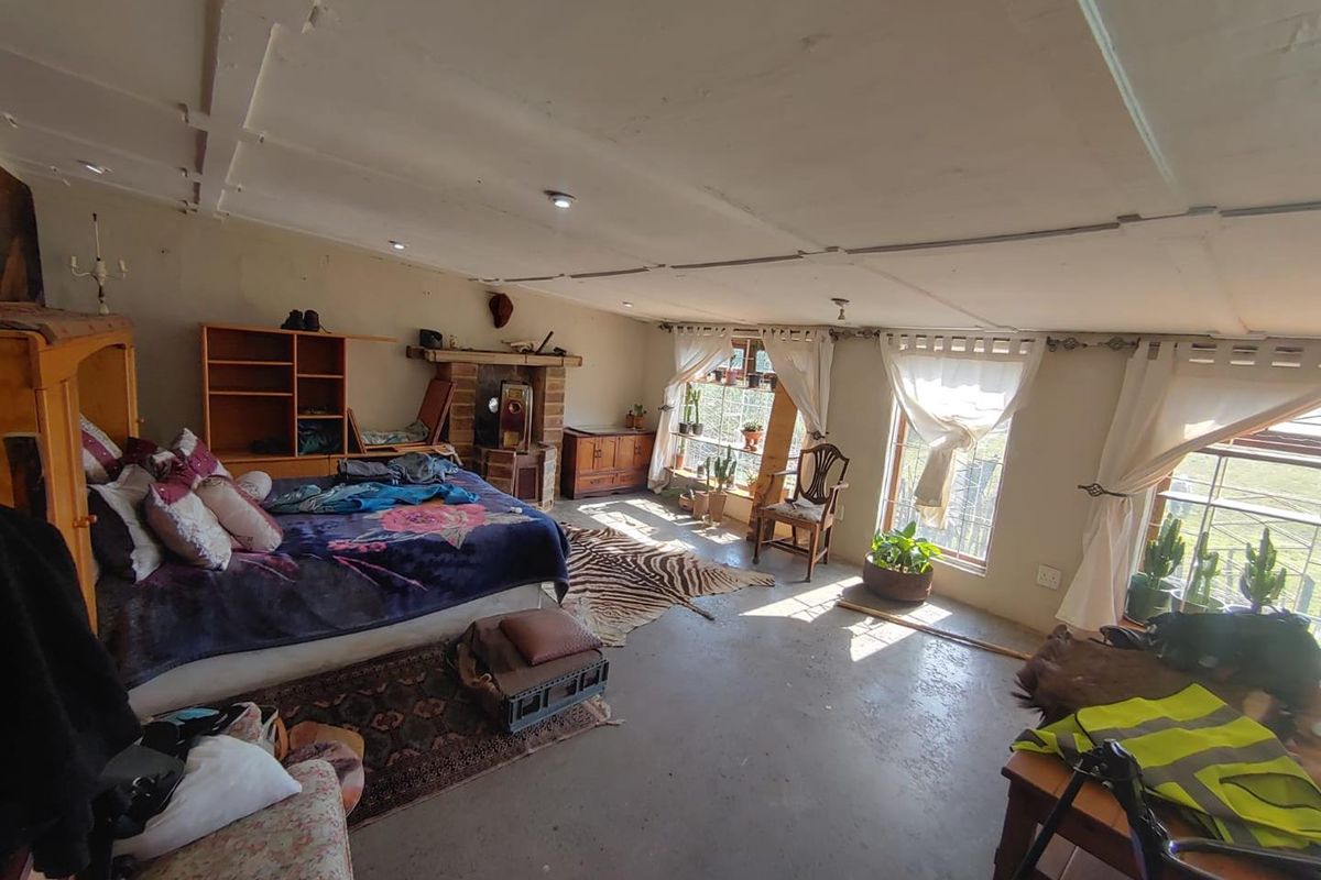 Spacious bedroom featuring a brick fireplace, concrete flooring, and large windows allowing for natural light.