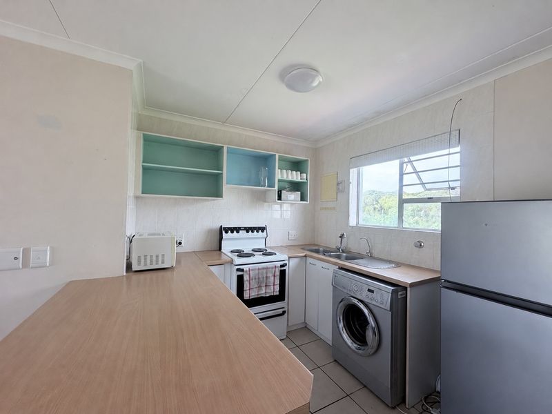 Functional kitchen featuring laminate countertops, built-in cabinetry, a freestanding stove, and tiled flooring with a window providing natural light.