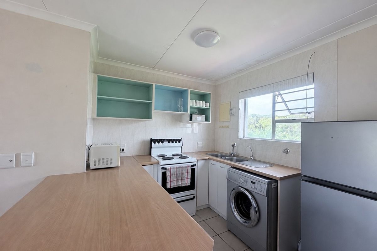 Functional kitchen featuring laminate countertops, built-in cabinetry, a freestanding stove, and tiled flooring with a window providing natural light.