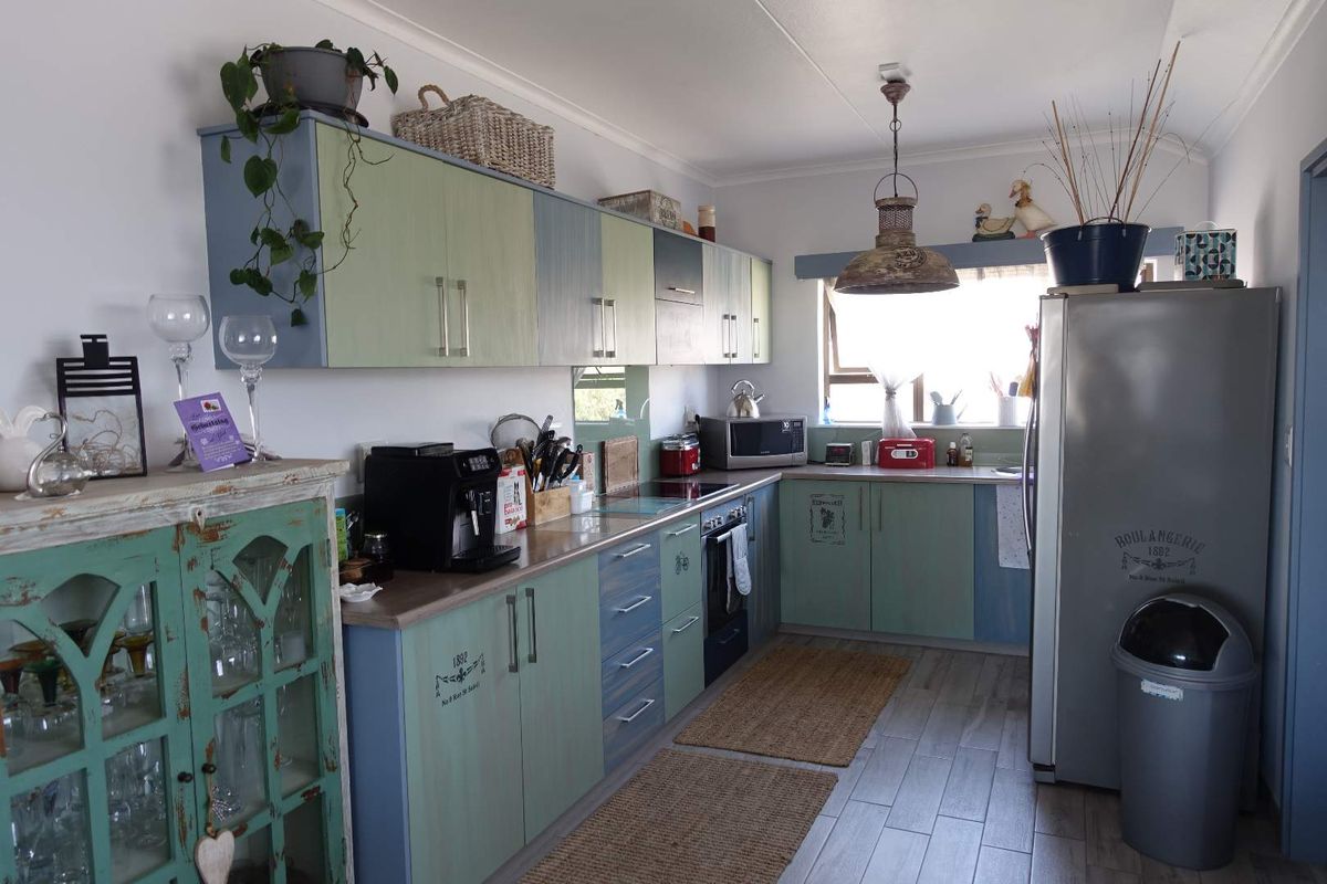 A functional kitchen featuring two-tone cabinetry, laminate countertops, a built-in oven, and a glass splashback with tiled flooring.