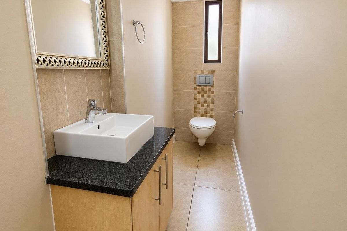 A modern guest bathroom featuring a wall-mounted toilet, a vanity cabinet with a granite countertop, and a vessel sink.